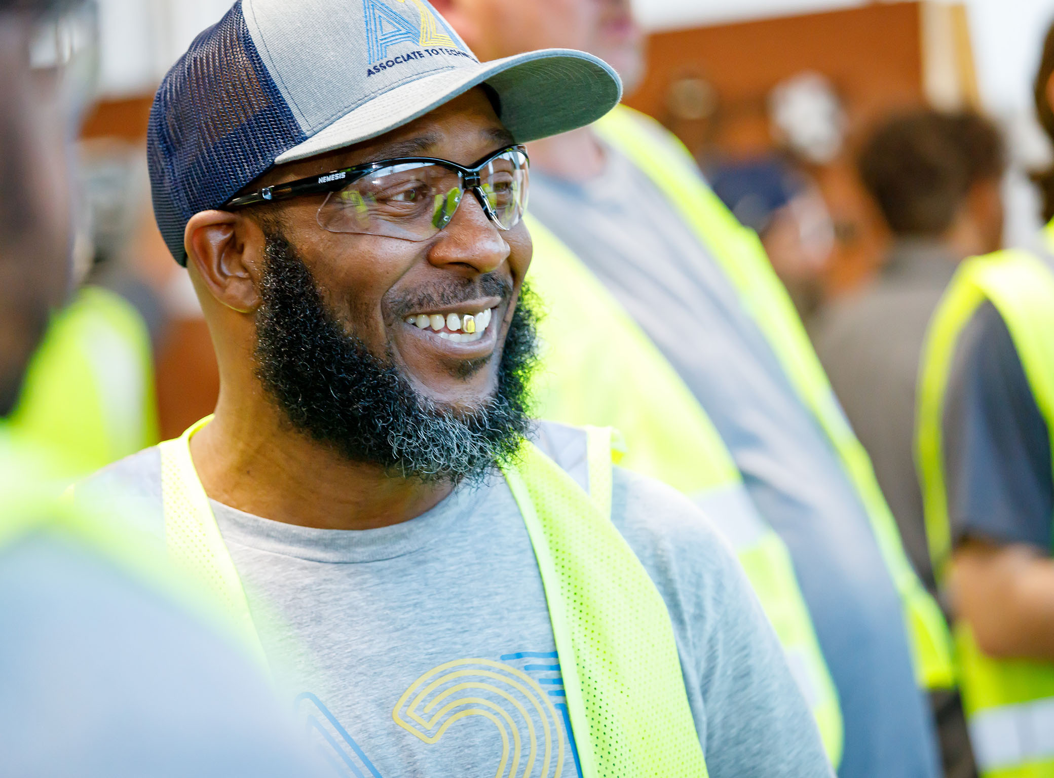 Hurk wears a ballcap with the Walmar A2T logo and smiles during class with other associates.