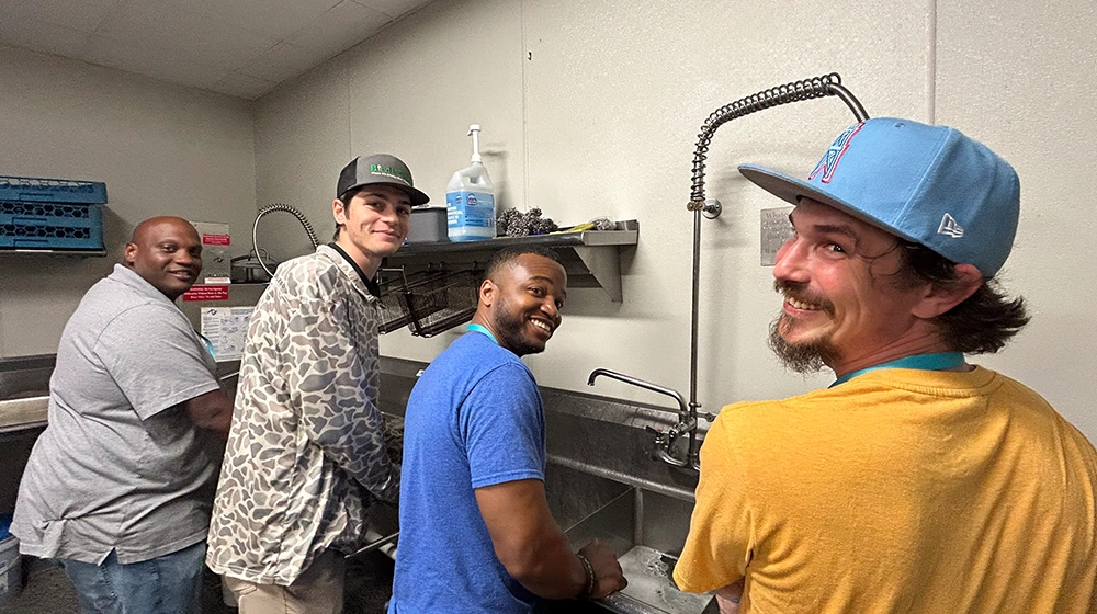 Smiling coworkers washing dishes in kitchen
